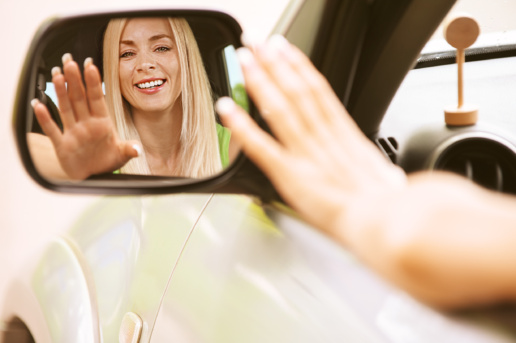 Woman driving and saying thank you through driver side mirror